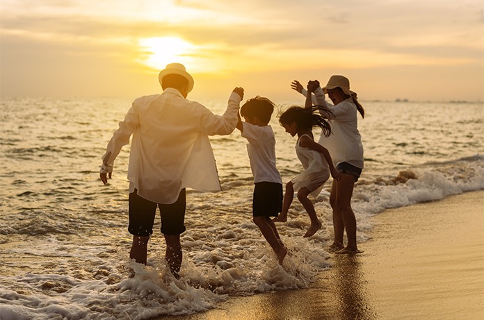 Grupo disfrutando en la orilla del mar mientras saltan entre las olas durante el atardecer