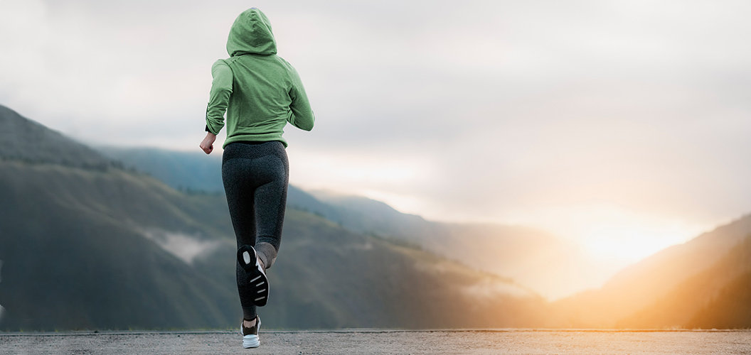 Joven corriendo por un valle hacia el atardecer